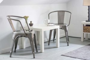 Two chairs siting across each other by a small white table