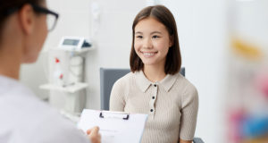 Asian young women smiles as she talks to doctor