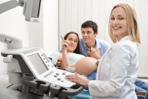 Pregnant couple watching Ultrasound results with a nurse.