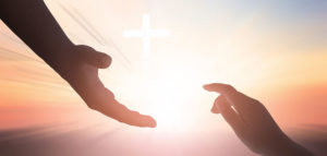 two hands reaching for each other with cross in center