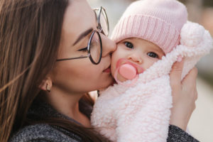 Mom kissing baby girl whole is bundled up