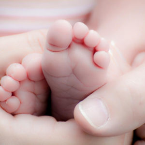 parents hand holding baby feet