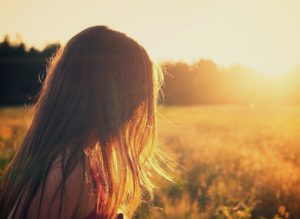 Little girl walking through field at sunset