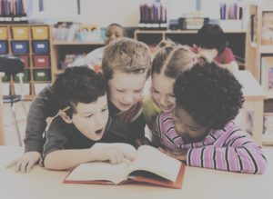Four kids sharing a book in a classroom
