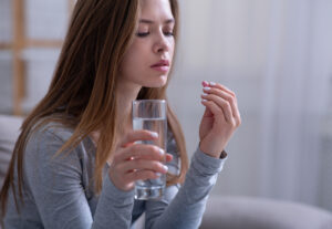 Unhappy young woman taking abortion pill at home