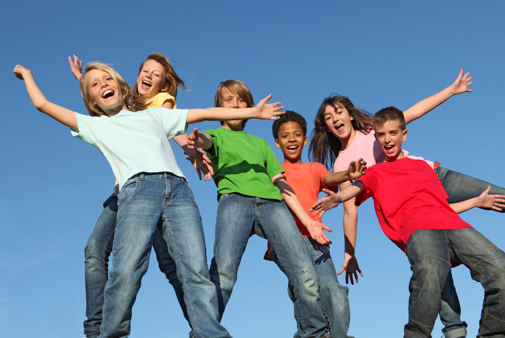 Group of happy smilling kids with arms outstretched playing at summer camp